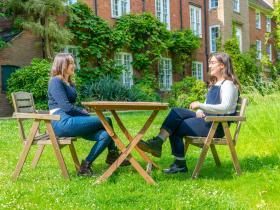 Two students sitting at an outdoor table having a conversation