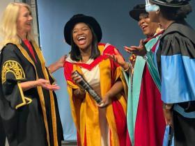 Vee Kativhu in a yellow and red academic gown with members of the University of Bradford