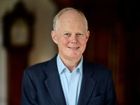 Photo of Andrew Macdonald, who is wearing a dark blue suit with a light blue shirt
