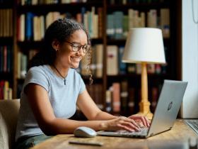 A female student sits with her laptop in the LMH library