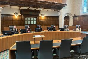 A photo of six students sitting at chairs at the UK High Court