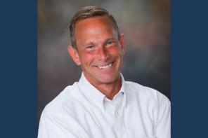 A man in a white shirt smiling at the camera