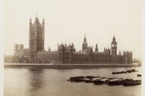 Old black and white photo of the Houses of Parliament, with the River Thames in the foreground