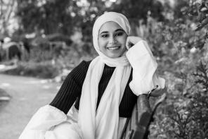 Black and white photo of Sharifah Alihinai sitting on a bench under a tree
