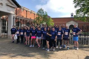 A group of people dressed in running clothes standing outside the gates of Lady Margaret Hall