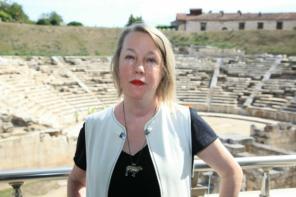 A.E. Stallings, a woman with short blonde hair, stands in front of a greek ampitheatre