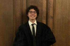Photo of Cem Kozanoglu, who has short dark curly hair and is wearing a black Oxford academic gown
