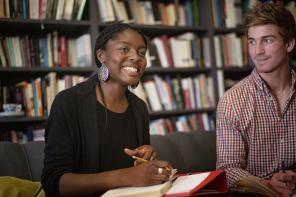 Two students enjoying a tutorial with a bookshelf in the background