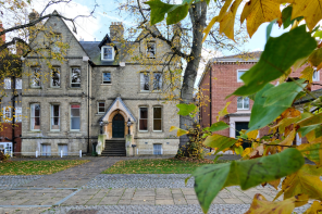 An old Victorian building seen through a screen of leaves tinged with autumn colour