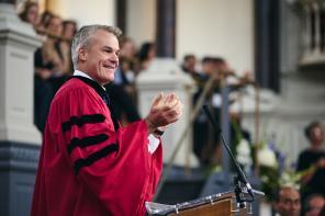 Professor Stephen Blyth in a red academic gown speaking in the Sheldonian
