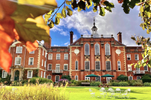 A large red brick building seen through a screen of autumn leaves