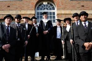 A group of people dressed in black academic dress standing on some steps