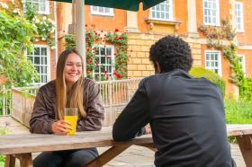 Student having a drink on bench outside LMH Bar