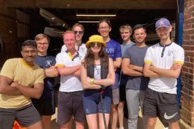 A group of students standing in the sunshine outside of the LMH boathouse