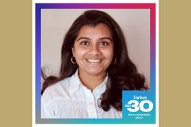 Vishnupriya Rajgarhia, an Indian woman with long dark brown hair and brown eyes, smiling at the camera