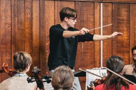 Felix Kirkby conducting a group of orchestral musicians