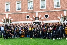 A large group of people standing together celebrating with their hands in the air