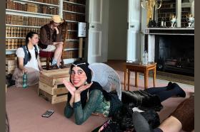 Students in costume relax while preparing for a performance of their play in a large stately home