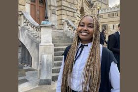 Lynnie Ngũgĩ, a young Black woman with long blonde and brown braids wearing Oxford academic dress