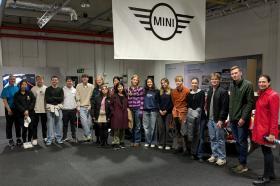 A group of students standing together in a large room with a 'Mini' sign hanging from the ceiling