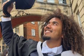 Ras.I Martin, who wears a black and white graduation gown, standing underneath the Hertford College bridge in Oxford