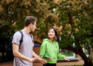 A male student and a female student walking outside talking to one another