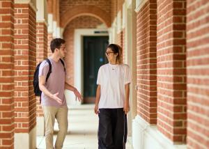 A male and female student walking along a red brick corridor