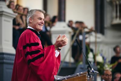 Professor Stephen Blyth in a red academic gown speaking in the Sheldonian